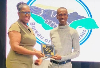 Principal Director, Bureau of Gender Affairs, Sharon Coburn Robinson (left), presents Jermaine Hurst with a plaque during a Father’s Day Ceremony in 2023.