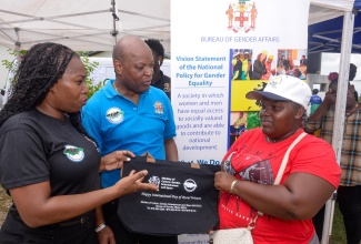 Acting Director for the Community Liaison Unit at the Bureau of Gender Affairs (BGA), Nardia McLaren (left), presents a branded bag to Merissa Reader during the International Day of Rural Women (IDRW) 2024 event on Wednesday (October 9), at the Portland Cottage Primary School in Clarendon. Looking on is Acting Research Officer at the BGA, Gerald McDermott.