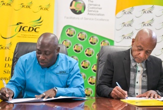 Deputy Chairman of the Jamaica Customer Service Association (JaCSA) and Chairman of National Customer Service Week, Richard Rowe (left), and Executive Director of Jamaica Cultural Development Commission (JCDC), Lenford Salmon, sign a Memorandum of Understanding (MOU) to formalise the long-standing partnership between the entities in coordinating the annual Jamaica Customer Service Competition. The signing took place on Friday (October 11) at the JCDC boardroom in Kingston. 