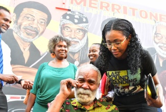 Racquel Blake (right) comforts her uncle, Director of Merritone Music, Monte Blake (in wheelchair), who was emotional at the unveiling of the Merritone Music Blake Family Mural on Wednesday (October 23) at the Kingston Creative art district on Water Lane, downtown Kingston. In the background are Director of Merritone Music, Monique Blake and Director of Culture at the Ministry of Culture, Gender, Entertainment and Sport, Joanne Archibald.

