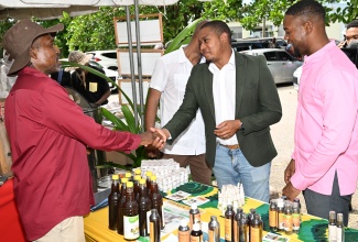 Minister of Agriculture, Fisheries and Mining, Hon. Floyd Green (second right), greets beekeeper, Glenwick Clarke (left), at the St. James Bee Farmers Association's Healthy Lifestyle Day, held at the St. James RADA Office in Catherine Hall, on Thursday, October 3. At right  is Mayor of Montego Bay and Chairman of the St. James Municipal Corporation, Councillor Richard Vernon.

