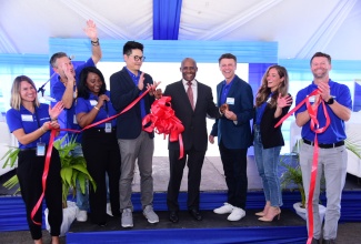 Minister of Industry, Investment and Commerce, Senator the Hon. Aubyn Hill (fourth right), cuts the ribbon to officially open Centerfield’s location in Portmore, St. Catherine, on Tuesday (October 22). He is joined by staff and executives of the company.

