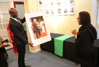 Jamaica’s Ambassador to the United States, Her Excellency Audrey Marks (right), is surprised with the presentation of a photograph of her receiving the National Honour, the Order of Jamaica (OJ), from Governor General, His Excellency the Most Hon. Sir Patrick Allen, on National Heroes Day (October 21), at King’s House in Kingston.  The photograph was presented by the Head of Accreditation at the Embassy of Jamaica in Washington DC, Dameon Eunick.

