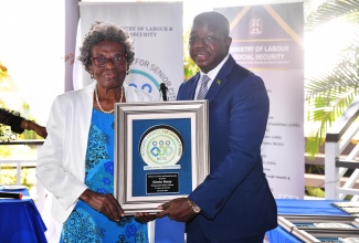 Minister of Labour and Social Security, Hon. Pearnel Charles Jr. presents Gloria Facey with the Distinguished Senior Citizen Award, at the National Council for Senior Citizens (NCSC) regional awards ceremony held at The Verandah in Clarendon on Thursday (October 3).  

