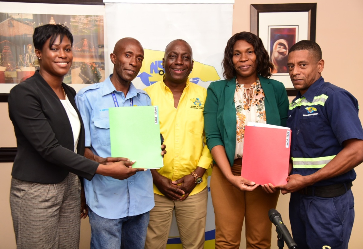 Executive Director of the National Solid Waste Management Authority (NSWMA), Audley Gordon (centre), joins in the handover of permanent-employment letters to workers at the agency’s Half-Way Tree Road office in St. Andrew on Monday (October 14). From left, Director of Corporate Services, Sheenique Johnson, makes a presentation to driver, Deon Griffiths, while Director of Operations, Aretha McFarlane, presents sanitation worker, Ian Rowe, with his letter of employment. NSWMA workers who were previously on contract, are being transitioned to 3,813 permanent positions.