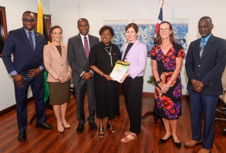 Minister of Culture, Gender, Entertainment and Sport, Hon. Olivia Grange (centre), and United Kingdom (UK) Minister for Latin America and the Caribbean, Baroness Jennifer Chapman (third right), display a signed agreement for a feasibility study for the National Stadium Redevelopment Project. Occasion was a press conference at the Culture Ministry in New Kingston on Tuesday (October 15) to provide an update on the project. They are joined by (from left) Supernumerary Permanent Secretary in the Culture Ministry, Dean-Roy Bernard; Minister of Foreign Affairs and Foreign Trade, Senator the Hon. Kamina Johnson Smith; Minister of Finance and the Public Service, Dr. the Hon.  Nigel Clarke; British High Commissioner to Jamaica, Judith Slater; and Permanent Secretary in the Ministry of Culture, Gender, Entertainment and Sport, Denzil Thorpe.

