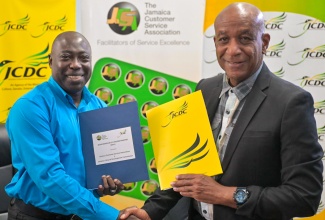 Deputy Chairman, Jamaica Customer Service Association (JaCSA) and Chair, National Customer Service Week (NCSW), Richard Rowe (left), and Executive Director, Jamaica Cultural Development Commission (JCDC), Lenford Salmon, shake hands following the signing of a Memorandum of Understanding (MOU) to formalise the entities’ partnership in coordinating the annual Jamaica Customer Service Poetry Competition. The MOU was signed during a brief ceremony at the JCDC’s head office in Kingston on Friday (October 11).