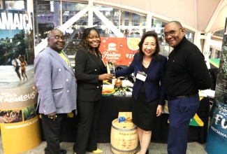 Minister-Counsellor for Trade at the Embassy of Jamaica in Washington DC, Alicia Taylor, presents Jamaican Blue Mountain Coffee to Secretary of the State of Maryland, Susan C. Lee, who stopped at Jamaica’s booth at Maryland’s State of the Ports and Global Flavor Showcase held recently in Baltimore.  Sharing the moment (from left) are: Travel Consultant, Chris Davis and Security Attaché at the Embassy, Ewon Simms.