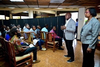 Minister of Labour and Social Security, Hon. Pearnel Charles Jr., (second right), addresses potential candidates for placement in the Overseas Employment (farmwork) Programme in Canada and the United States (US), during a recruitment exercise at the Jamaica Conference Centre in downtown Kingston on Thursday (November 28). Looking on is Acting Permanent Secretary in the Ministry, Dione Jennings.

