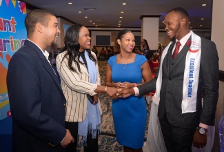 Permanent Secretary, Ministry of Education, Skills, Youth and Information, Dr. Kasan Troupe (second left), greets teacher at New Works Primary and Infant School, Jovan Dwyer, during Carlong Publishers (Caribbean) Limited’s Teachers’ Appreciation Luncheon and Awards Ceremony at the Jamaica Pegasus Hotel in New Kingston on Wednesday (November 20). Others (from left ) are: Carlong Publishers General Managers, Jason and Candice Carby.