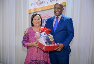 Minister of Industry, Investment and Commerce, Senator the Hon. Aubyn Hill (right) is presented with a gift basket by Founder, Honey Bun Foundation, Michelle Chong, at a cocktail reception hosted by the Foundation’s Advisory Committee at the Terra Nova All-Suite Hotel in Kingston on November 28.