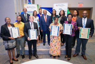 Minister of Industry, Investment and Commerce, Senator the Hon. Aubyn Hill (back row, fourth left), and Manager, National Certification Body of Jamaica (NCBJ), Navenia Wellington Ford (back row, third left), share a photo opportunity with representatives of nine organisations which received certification during the National Certification Body of Jamaica’s (NCBJ) Certificate Handover Ceremony on Wednesday (November 13) at the AC Hotel by Marriott Kingston.

