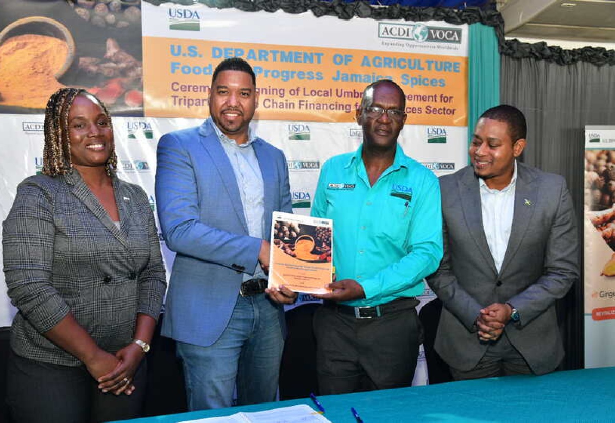 Minister of Agriculture, Fisheries and Mining, Hon. Floyd Green (right) and Agricultural Specialist, United States Department of Agriculture (USDA)  Kingston, Rasheeda Hall Hanson  (left), look on as Chief of Party, USDA Food for Progress Jamaica Spices (JaSPICES) Project, Dr. Ronald Blake (second right) presents Chief Executive Officer, Carbyne Capital Investments Limited, Rajiv Ebanks, with the signed agreement to provide financing for the spices sector, during a ceremony at the Terra Nova Hotel in Kingston on Thursday (Nov. 21).