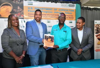 Minister of Agriculture, Fisheries and Mining, Hon. Floyd Green (right) and Agricultural Specialist, United States Department of Agriculture (USDA)  Kingston, Rasheeda Hall Hanson  (left), look on as Chief of Party, USDA Food for Progress Jamaica Spices (JaSPICES) Project, Dr. Ronald Blake (second right) presents Chief Executive Officer, Carbyne Capital Investments Limited, Rajiv Ebanks, with the signed agreement to provide financing for the spices sector, during a ceremony at the Terra Nova Hotel in Kingston on Thursday (Nov. 21).