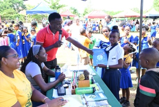 Jamaica 4-H Clubs Manager for St. Ann, Tedroy Gordon (third from left), presents a spot prize to Gibraltar All-age School student, Romonia Coore, during the Runaway Bay Primary and Infant School 4-H Club’s open day held on Thursday (Oct. 31). Looking on is Forest Technicians at the Forestry Department, Kerry Ann Newland-McLean (left) and Mackeda Coombs.