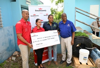 Minister of Agriculture, Fisheries and Mining, Hon. Floyd Green (second right), and State Minister in the Ministry, Hon. Franklin Witter (right), accept a symbolic cheque for $6.2 million to purchase a generator from Chief Executive Officer, GK Foods Domestic, Frank James, and GK’s General Counsel and Chief Corporate Secretary, Gail Moss-Solomon, during a handover ceremony in Hounslow, St. Elizabeth, on November 1. Farming supplies , valued more than $3 million, were also handed over by the company. The provisions form part of the multi-stakeholder Hurricane Beryl recovery assistance being extended to farmers in the parish.  

