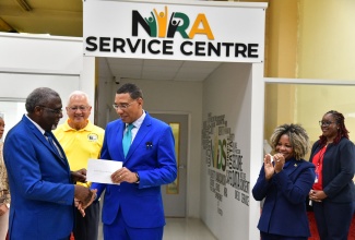 Prime Minister, Dr. the Most Hon. Andrew Holness (centre), accepts his national identification card from Chairman of the National Identification Registration Authority (NIRA), Bishop the Hon. Conrad Pitkin, during the official launch of the NIRA at the Central Sorting Office (CSO) in Kingston on Friday (November 15). Looking on is Minister of Justice, Hon. Delroy Chuck (second left), and Minister of Education, Skills, Youth and Information, Senator Dr. the Hon. Dana Morris Dixon (second right).