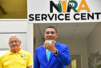 Prime Minister, Dr. the Most Hon. Andrew Holness (right), displays his national identification card during the official launch of the National Identification Registration Authority (NIRA) at the NIRA Centre, Central Sorting Office (CSO) in Kingston on Friday (November 15). Looking on is Minister of Justice, Hon. Delroy Chuck.

