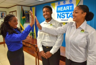 Managing Director, HEART/NSTA Trust, Dr. Taneisha Ingleton (left), shares a ‘high-five’ with Learning and Investment for Transformation (LIFT) Programme participant, Olivia Reid (right), at the agency’s Corporate Office on Oxford Road in Kingston on November 1. Sharing the moment is LIFT participant, Justin McCarthy.

