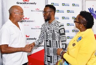 Patron of Child Month, Hon. Douglas Orane (left), greets Director of the African Caribbean Institute of Jamaica/Jamaica Memory Bank (ACIJ/JMB), Dr. Kirt Henry, during the National Child Month Committee (NCMC) Youth Form, which was held at the Caenwood Centre Auditorium in Kingston on November 1. Looking on is NCMC Chair, Nicole Patrick Shaw. 

