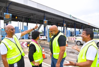 Group Chief Executive Officer (CEO), TransJamaican Highway Limited and Jamaican Infrastructure Operator Limited, Ivan Anderson (left) points to the rebranded toll booth, at a ceremony for the Rebranding of Highway 2000 East-West to TransJam Highways, held on Friday (November 29) at the Portmore Toll Plaza Recreational Field in St. Catherine. Others (from second left) are Acting CEO, Toll Authority, Kerry Kay Holness; Group Product Manager, Interlinc, Daniel Hew; and Group Chief Operating Officer, TransJamaican Highway Limited and Managing Director of Jamaican Infrastructure Operator Limited, Colin Murray.