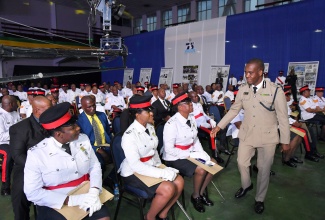 Police Commissioner, Dr. Kevin Blake (standing), congratulates members of the Jamaica Constabulary Force (JCF) who were recognised during the organisation’s Honours and Awards Ceremony at the National Arena on Thursday (November 28).