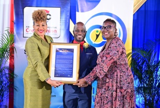 Computer Services Manager, Jamaica Information Service (JIS), André Allen, receives his 2024/25 Civil Servant of the Year Award in the Managerial Category, from Assistant General Manager, First Heritage Co-operative Credit Union (FHCCU), Michelle Tracey (left), and Acting Deputy Financial Secretary, Ministry of Finance and the Public Service, Lois Walters, during the presentation ceremony at the Terra Nova All-Suite Hotel in St. Andrew on Friday (November 15).