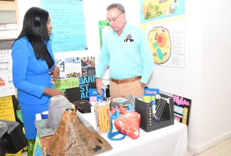 Minister of Science, Energy, Telecommunications and Transport, Hon. Daryl Vaz, listens as Senior Teacher at Immaculate Conception High School in St. Andrew, Kadesha Croney, highlights science projects on display during the annual conference of the Association of Science Teachers of Jamaica (ASTJ) at the Bahia Principe Resort in Runaway Bay, St. Ann, on November 13.