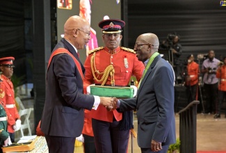 Moderator of the United Church in Jamaica and the Cayman Islands, Rev. Gary Harriott (right), receives the insignia for the Order of Distinction in the Rank of Commander (CD) from Governor-General, His Excellency the Most Hon. Sir Patrick Allen, during the Ceremony of Investiture of National Honours and Awards at the National Indoor Sports Centre in Kingston on National Heroes Day, Monday, October 21.  