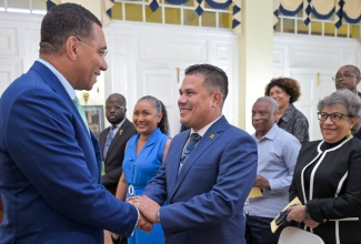 Prime Minister, Dr. the Most Hon. Andrew Holness (left), congratulates Minister without Portfolio in the Ministry of Economic Growth and Job Creation, Hon. Matthew Samuda, during his swearing-in ceremony at King
