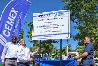 Prime Minister, Dr. the Most Hon. Andrew Holness (right), and Managing Director, Carib Cement Company Limited, Jorge Martinez Mora (centre), unveil the design for the new concrete road at Bay Farm Villa Close in St. Andrew West Central which was officially opened on Thursday (November 21). Sharing the moment is Industrial and Building Solutions Manager, Carib Cement Company, André Nelson.