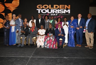 Minister of Tourism, Hon. Edmund Bartlett (sixth from left, standing), and Permanent Secretary in the Ministry of Tourism, Jennifer Griffith (seventh from left, standing) join the Golden Tourism Day Awards recipients in a photo opportunity, during a ceremony held at the Montego Bay Convention Centre in Rose Hall, St. James on Sunday (December 15).