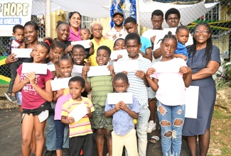 Mayor of Montego Bay and Chairman of the St. James Municipal Corporation, Councillor Richard Vernon (back, centre); Chief Executive Officer, St. James Municipal Corporation, Naudia Crosskill (third left, back row); Philanthropist, Sandra Miller-Hall (fourth left, back row); Shelter Manager of the Refuge of Hope, Junice Woolery-Norman (right), shares a light moment with children of Albion, St. James, during an outreach at the Refuge of Hope shelter in Albion, St. James, on Friday, December 20.

