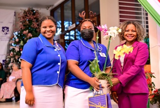 Minister of Education, Skills, Youth and Information, Senator Dr. the Hon. Dana Morris Dixon (right), accepts a token from students of Immaculate Conception High School in Kingston, during the institution’s prize giving ceremony on Wednesday (December 18). Making the presentation (from left) are Anna Campbell and Yolanne Allen.