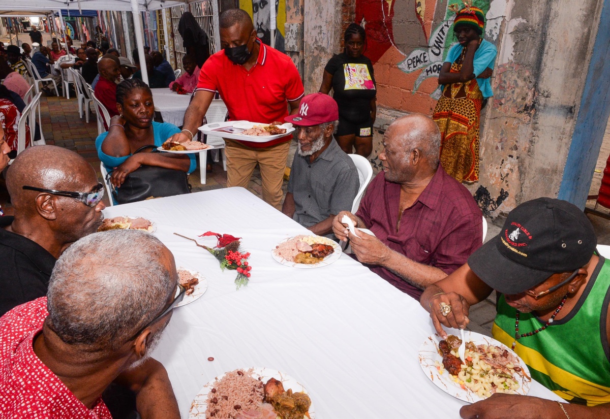 Kingston’s Mayor, Councillor Andrew Swaby (standing), serves meals to residents of the Marie Atkins Night Shelter and Desmond McKenzie Transitional Centre for the Homeless in the Corporate Area. They were treated during the Mayor’s Annual Christmas Day Feeding of the Homeless on Wednesday (December 25). The event was hosted on Water Lane in downtown Kingston.