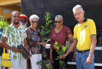Chairman of the Manchester Parish Development Committee (PDC), Anthony Freckleton (right), and Nursery Manager at the Jamaica Bauxite Institute (JBI), Chevion Morgan (left), hand out citrus seedlings to householders at the recent staging of Manchester Community Day at the Northern Caribbean University (NCU) in Mandeville.