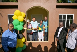 Prime Minister, Dr. the Most Hon. Andrew Holness (third left), cuts the ribbon to officially hand over a new house to New Social Housing Programme (NSHP) beneficiary, Claudette Linton (fourth left) and her mother Isolyn Finnigan (second left), during a ceremony held in Inverness, St. Ann, on December 12.  Sharing the occasion (from left) are Chairperson of the NSHP Oversight Committee, Judith Robb Walters; Minister of State in the Ministry of Finance and the Public Service and Member of Parliament for St. Ann South West , Hon. Zavia Mayne; Councillor of the Gibraltar Division, Cardell Wickham and Councillor for the Alexandria Division, Rohan Davidson.