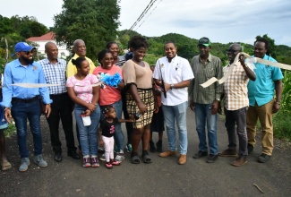 Minister of Agriculture, Fisheries and Mining, Hon. Floyd Green (fourth right), cuts the ribbon to officially open phase one of the newly rehabilitated Cornwall Top farm road in St. Elizabeth on November 28. Joining Mr. Green are (from left), Mayor of Black River, Councillor Richard Solomon; Councillor for the Lacovia Division, George Powell; State Minister in the Agriculture Ministry, Franklin Witter; Minister of State in the Ministry of Science, Energy, Telecommunications and Transport and Member of Parliament for St. Elizabeth North Western, Hon. J.C. Hutchinson (third right); Principal Director of Technical Services at the Rural Agricultural Development Authority (RADA), Winston Simpson (second right); and Director of Engineering Services, Clayton Williams (right). They are joined by farmer Dionne Blake (fifth right) and other members of the community. The thoroughfare was repaired as part of the Ministry’s National Farm Road Rehabilitation Programme. 