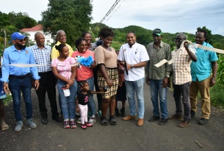 Minister of Agriculture, Fisheries and Mining, Hon. Floyd Green (fourth right), cuts the ribbon to officially open phase one of the newly rehabilitated Cornwall Top farm road in St. Elizabeth on November 28. Joining Mr. Green are (from left), Mayor of Black River, Councillor Richard Solomon; Councillor for the Lacovia Division, George Powell; State Minister in the Agriculture Ministry, Franklin Witter; Minister of State in the Ministry of Science, Energy, Telecommunications and Transport and Member of Parliament for St. Elizabeth North Western, Hon. J.C. Hutchinson (third right); Principal Director of Technical Services at the Rural Agricultural Development Authority (RADA), Winston Simpson (second right); and Director of Engineering Services, Clayton Williams (right). They are joined by farmer Dionne Blake (fifth right) and other members of the community. The thoroughfare was repaired as part of the Ministry’s National Farm Road Rehabilitation Programme.