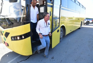 Minister of Science, Energy, Telecommunications and Transport, Hon. Daryl Vaz (foreground), and Member of Parliament for St. Thomas Western, James Robertson, disembark a Jamaica Urban Transit Company (JUTC) bus that plies one of the newly established JUTC routes in St. Thomas on Tuesday (December 10).