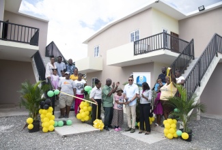 Prime Minister, Dr. the Most Hon. Andrew Holness (seventh right); and Minister of Local Government and Community Development and Member of Parliament for West Kingston, Hon. Desmond McKenzie (ninth right), celebrate with new homeowners during the ribbon cutting and handover of units at the Victoria Palms Housing Development relocation project in Denham Town, West Kingston on Friday (Dec. 13). Also sharing in the moment are Permanent Secretary in the Ministry of Local Government and Community Development, Marsha Henry Martin (ninth left); and Permanent Secretary in the Ministry of Economic Growth and Job Creation, Arlene Williams (sixth right).