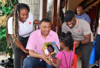 Prime Minister, Dr. the Most Hon Andrew Holness (centre) presents a gift to a ward of the State during a Christmas treat on Sunday (Dec. 15) on the Jamaica House back lawns in Kingston.  Sharing the moment are Burger King’s Assistant Brand Manager Rashai Graham (left) and Senior Brand Manager, Orion Aitken.

