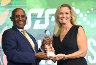 Minister of Industry, Investment and Commerce, Senator the Hon. Aubyn Hill, makes a presentation to Country Director for Conduent Jamaica, Lynda Langford, during the second Jamaica Special Economic Zone Authority (JSEZA) Sustain-A-Livity Awards ceremony on Thursday (December 5) at the AC Hotel by Marriott Kingston.

