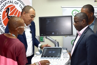 Minister of Health and Wellness, Dr. the Hon. Christopher Tufton (second left), looks at the features of the ultrasound machine valued US$96,356, donated by the National Health (NHF) to the Foetal Diagnosis and Therapy Unit at the University Hospital of the West Indies (UHWI), during the handover ceremony at the institution in St. Andrew on Tuesday (December 10). Others (from left) are Maternal Foetal Medicine Specialist, Dr. Nadine Johnson; Medical Officer of Health at the hospital, Dr. Carl Bruce; Chief Executive Officer of the NHF, Everton Anderson.