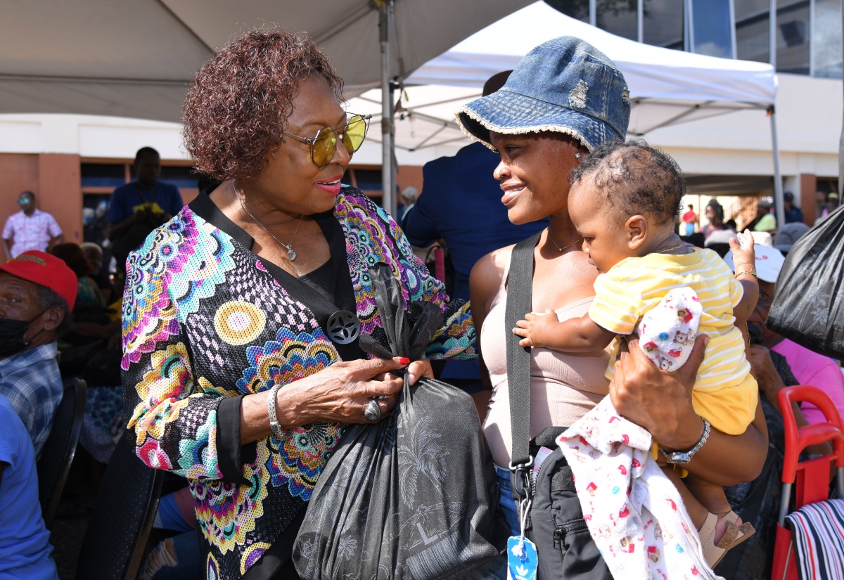 Minister of Culture, Gender, Entertainment, and Sport, and Member of Parliament for St. Catherine Central, Hon. Olivia Grange (left), shares a warm moment with Sanesha Gayle and her baby, Courtney Lobban, as they receive a care package during the annual Christmas treat hosted by the Houses of Parliament on Wednesday (December 18) at George William Gordon House, Kingston.

