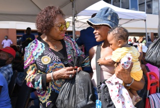 Minister of Culture, Gender, Entertainment, and Sport, and Member of Parliament for St. Catherine Central, Hon. Olivia Grange (left), shares a warm moment with Sanesha Gayle and her baby, Courtney Lobban, as they receive a care package during the annual Christmas treat hosted by the Houses of Parliament on Wednesday (December 18) at George William Gordon House, Kingston.

