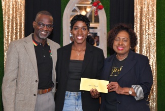 Culture, Gender, Entertainment and Sport Minister, Hon. Olivia Grange (right) makes a presentation to national 400 metres hurdles athlete, Janieve Rusell, during a function to handover grants to members of Jamaica