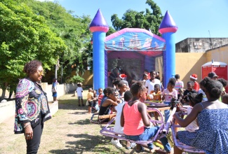 Minister of Culture, Gender, Entertainment and Sport, Hon. Olivia Grange, smiles as she observes children enjoying a fun ride during the annual Christmas treat hosted by the Houses of Parliament on Wednesday (December 18) at the Gardens of Parliament in Kingston. This year’s event featured a health village for senior citizens and kiddies park for children.