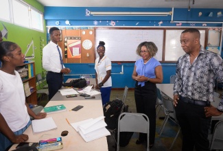 Minister of Education, Skills, Youth and Information, Senator Dr. the Hon. Dana Morris Dixon (second right), and Principal of Tarrant High School, Paul Hall (right), interact with students in the school’s Mathematics Laboratory on Thursday (December 19). The Minister taught a class on patterns and sequences in mathematics during the Ministry’s Christmas Mathematics Camp.