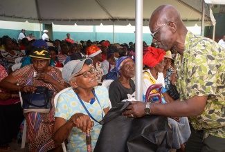 Minister of Local Government and Community Development and Member of Parliament for Kingston Western, Hon. Desmond McKenzie (right), presents senior citizen, Gwendolyn Morgan with a care package during the annual Christmas treat for the Elderly at the Tivoli Gardens Community Centre on Thursday (December 19).